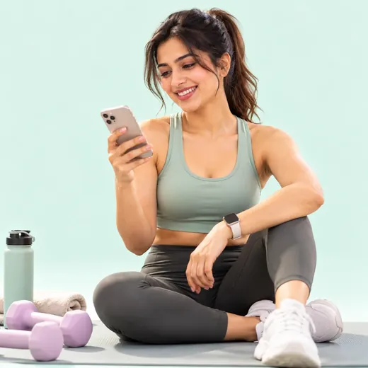 A woman in workout clothes checking her phone on a mat